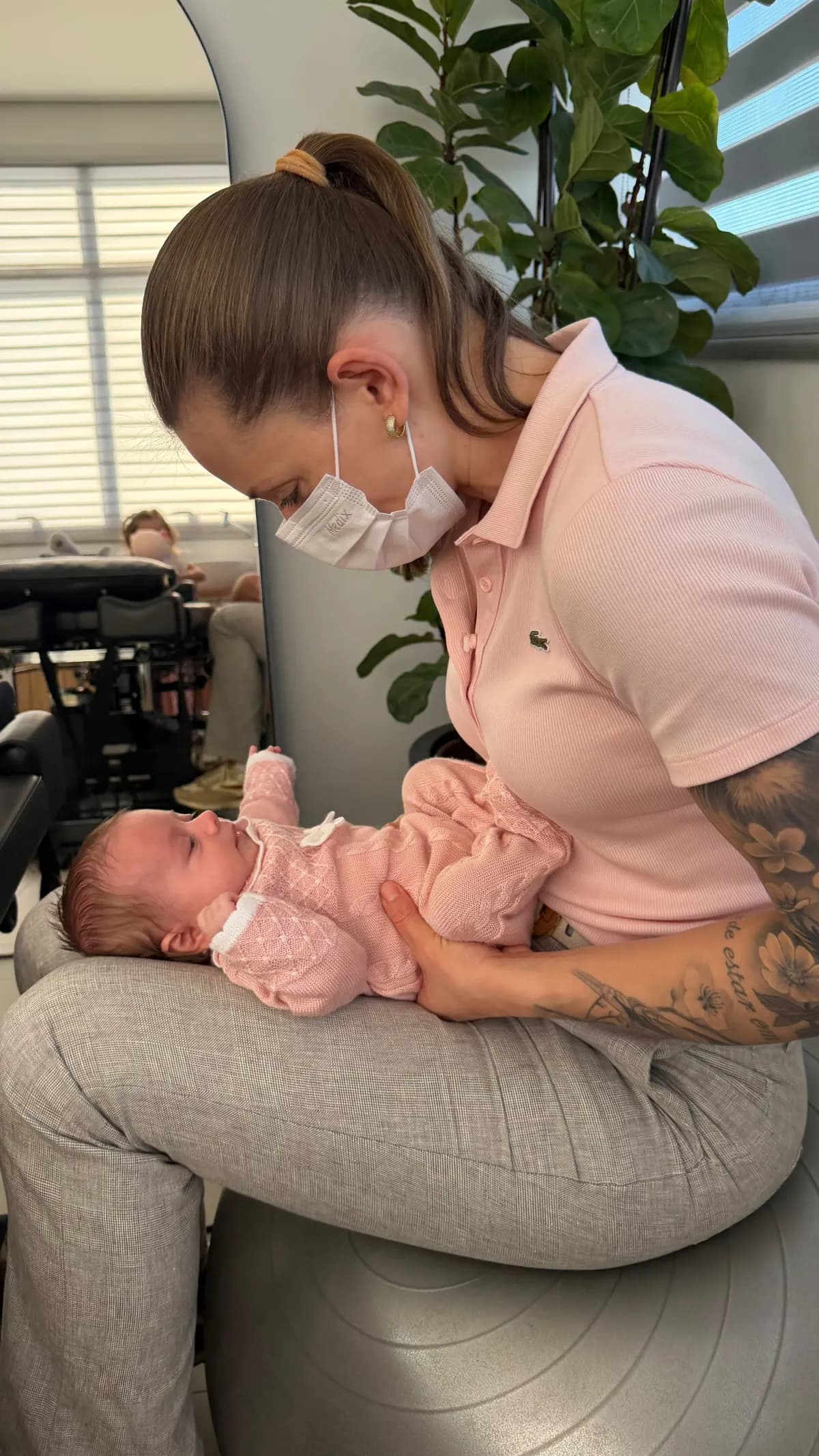 Dra. Simone Pryjmak atendendo um bebê com roupa rosa no consultório